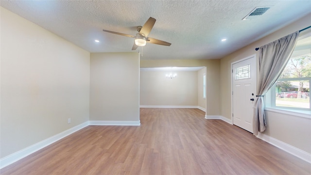 interior space featuring light wood-style floors, baseboards, visible vents, and ceiling fan with notable chandelier