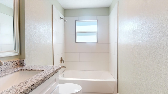 bathroom featuring tub / shower combination, a textured wall, vanity, and toilet