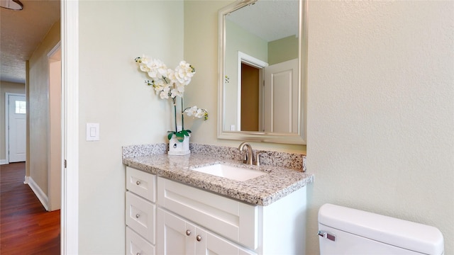 bathroom with baseboards, vanity, toilet, and wood finished floors