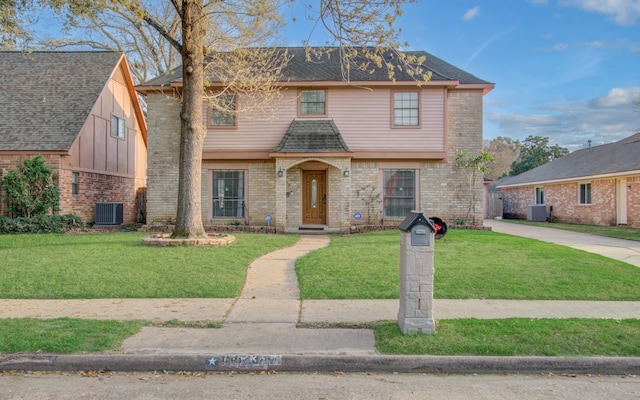 view of front of home featuring brick siding, roof with shingles, central AC, and a front lawn