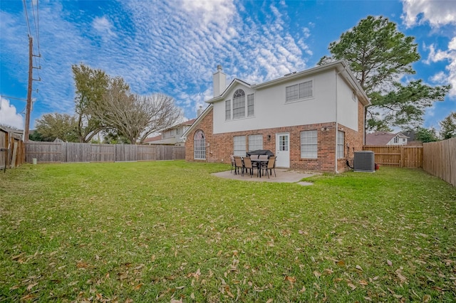 rear view of house with a patio, central AC, brick siding, a yard, and stucco siding