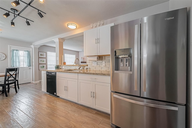 kitchen featuring tasteful backsplash, white cabinets, stainless steel fridge with ice dispenser, light wood-type flooring, and a sink