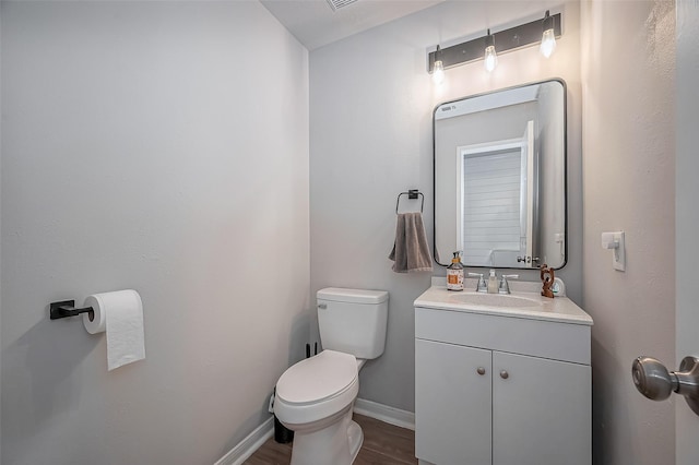 bathroom featuring wood finished floors, vanity, toilet, and baseboards