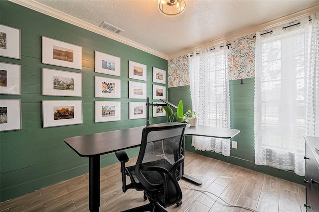 home office featuring a textured ceiling, ornamental molding, wood finished floors, and visible vents