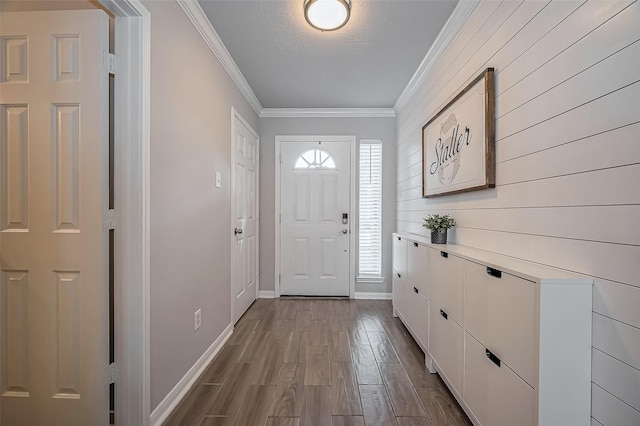 foyer entrance featuring ornamental molding, dark wood-style flooring, a textured ceiling, and baseboards