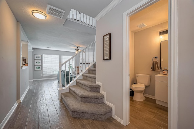 staircase with visible vents, baseboards, and wood finished floors