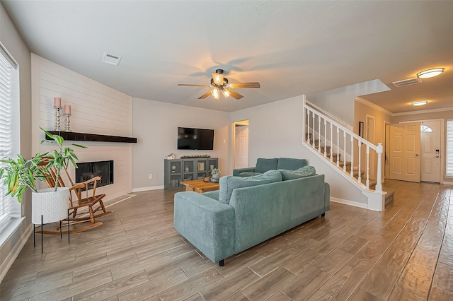 living room featuring stairs, a large fireplace, visible vents, and light wood-style floors