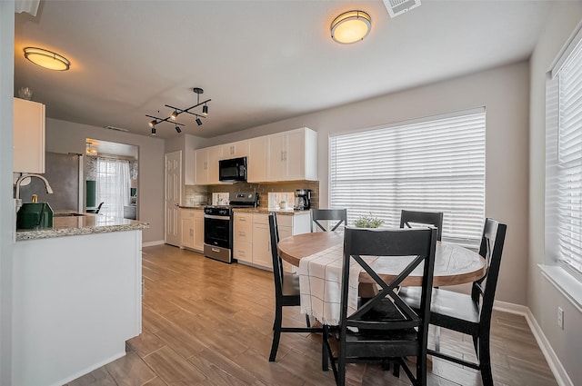 interior space with baseboards, visible vents, and light wood finished floors