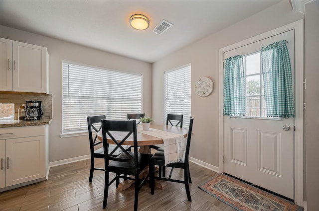 dining area featuring baseboards, visible vents, and wood finished floors