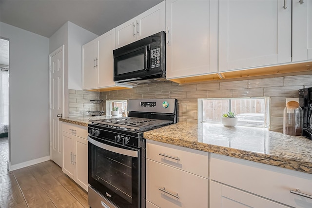 kitchen with stainless steel range with gas cooktop, black microwave, decorative backsplash, and light stone counters