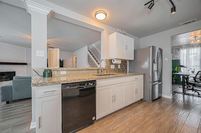 kitchen featuring black dishwasher, stainless steel refrigerator with ice dispenser, visible vents, light wood-style floors, and a sink