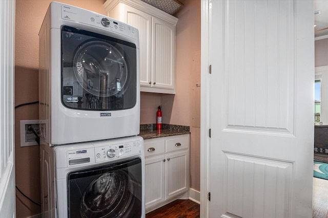 172 Ocean View Dr, Crystal Beach, TX 77650 - laundry area featuring stacked washer and clothes dryer, cabinet space, and dark wood-type flooring