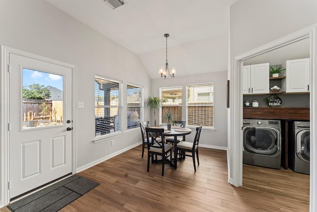 dining area with wood finished floors, visible vents, an inviting chandelier, lofted ceiling, and washer and clothes dryer