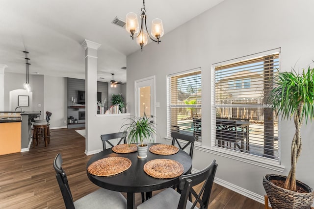 dining space featuring dark wood-style floors, visible vents, baseboards, ornate columns, and ceiling fan with notable chandelier