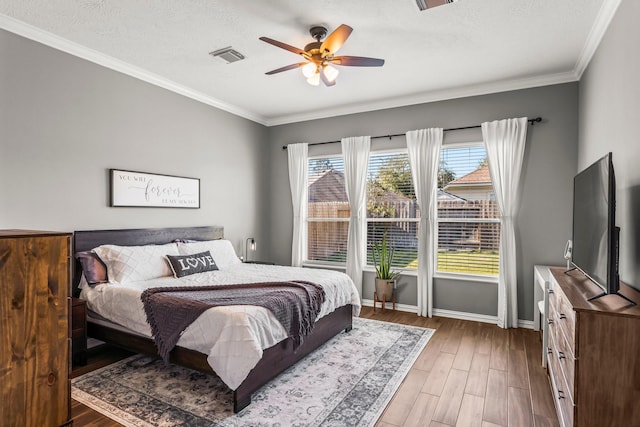 bedroom with visible vents, ornamental molding, baseboards, and wood finished floors