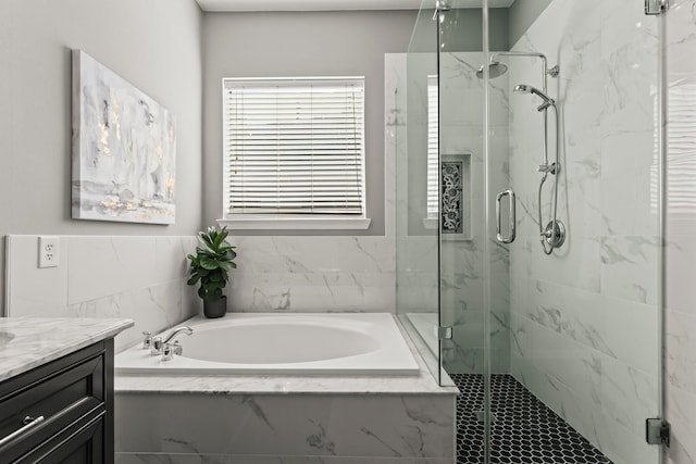 bathroom with a marble finish shower, vanity, and a garden tub