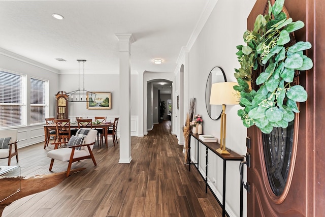 entrance foyer featuring visible vents, crown molding, decorative columns, arched walkways, and dark wood-style floors