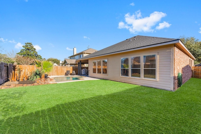 back of house with a yard, brick siding, and a fenced backyard