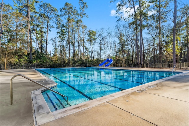 community pool featuring a water slide and fence