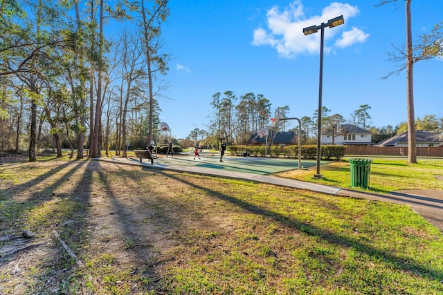 view of community with community basketball court, a lawn, and fence