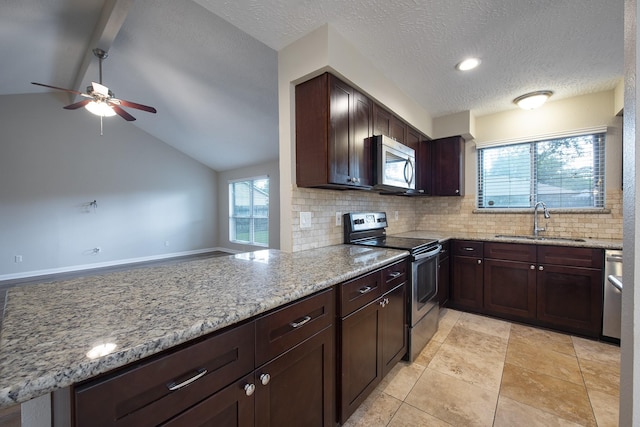 kitchen featuring a peninsula, light stone countertops, appliances with stainless steel finishes, and a sink