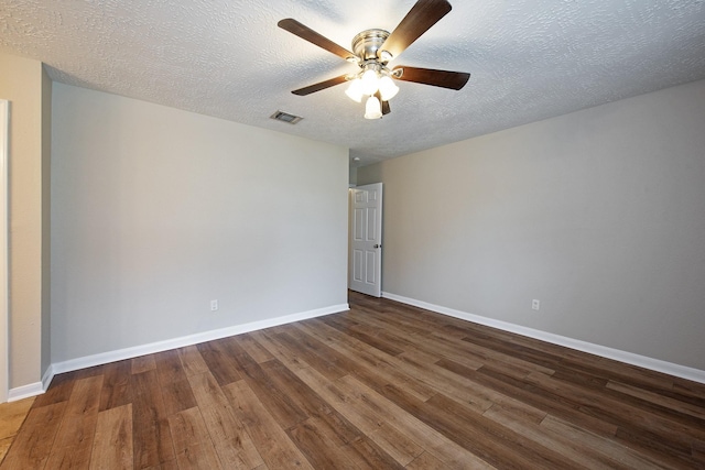 empty room with visible vents, a textured ceiling, baseboards, and wood finished floors