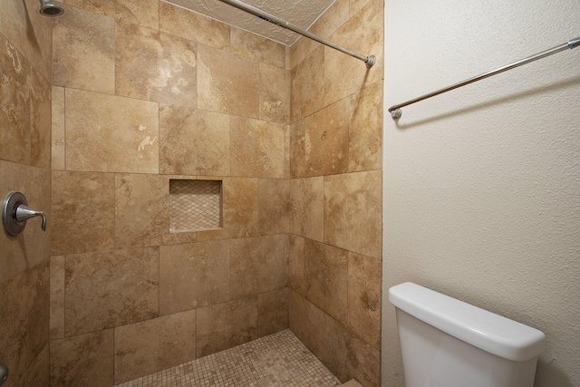 full bath with toilet, a textured wall, and a tile shower