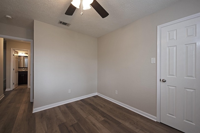 unfurnished bedroom with a ceiling fan, baseboards, visible vents, dark wood finished floors, and a textured ceiling