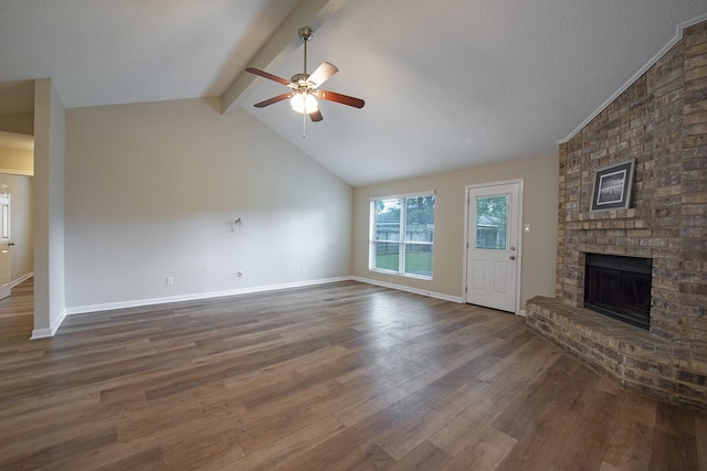 unfurnished living room with wood finished floors, vaulted ceiling with beams, a fireplace, and ceiling fan