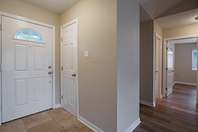 entrance foyer featuring baseboards, a textured ceiling, and wood finished floors