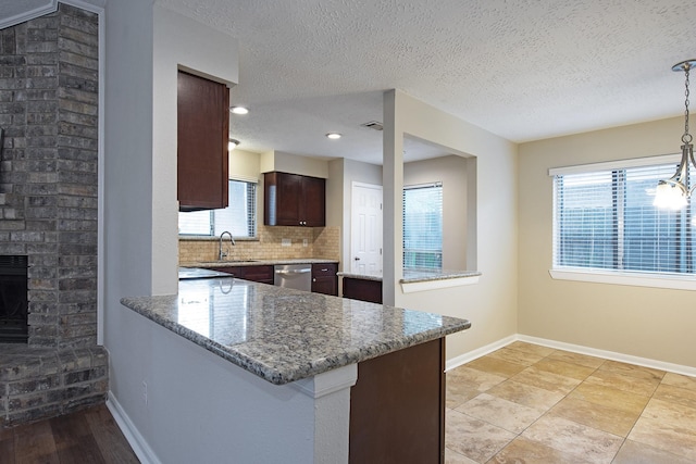 kitchen with decorative backsplash, a peninsula, baseboards, and a sink