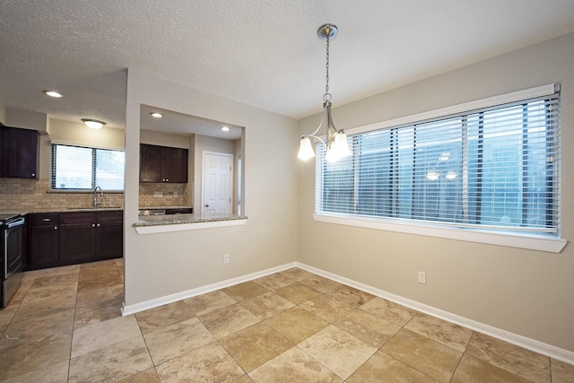 unfurnished dining area featuring baseboards, an inviting chandelier, recessed lighting, a sink, and a textured ceiling