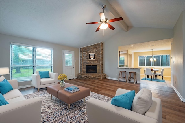 living room with lofted ceiling with beams, a brick fireplace, wood finished floors, and baseboards