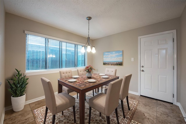 dining area featuring light tile patterned floors, a textured ceiling, and baseboards