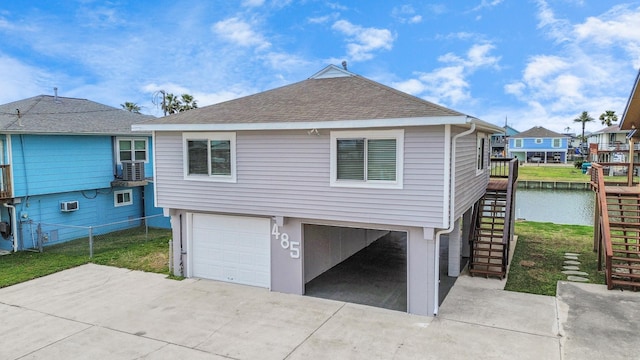 exterior space with driveway, a shingled roof, stairway, and an attached garage