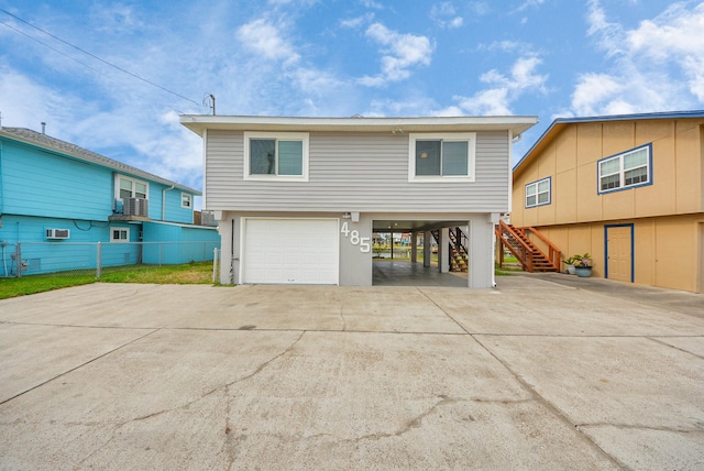 view of front of house with a wall mounted AC, fence, a carport, driveway, and stairs