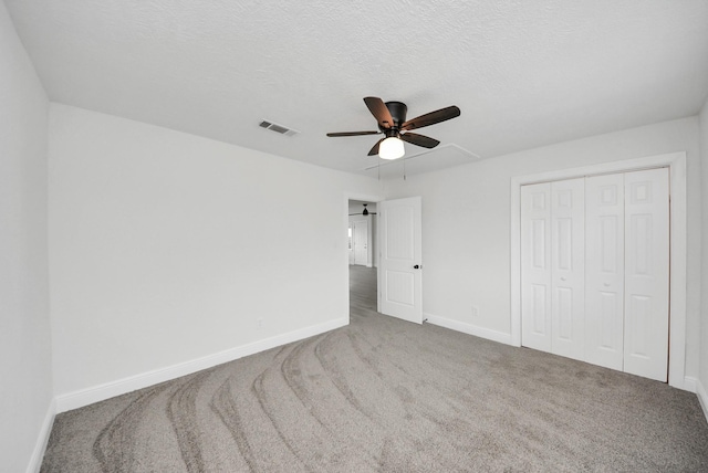 unfurnished bedroom featuring a textured ceiling, carpet floors, visible vents, baseboards, and a closet