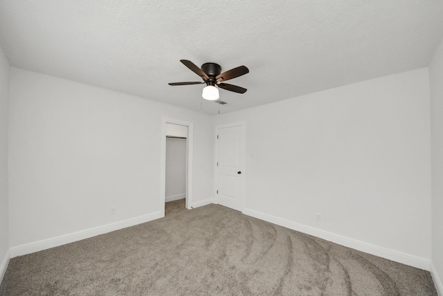 carpeted empty room featuring a ceiling fan, baseboards, and a textured ceiling