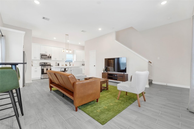 living area featuring wood tiled floor, stairway, baseboards, and recessed lighting