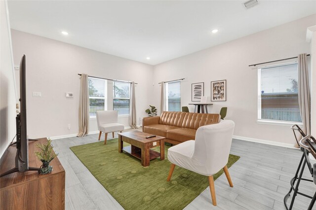 living area with light wood-style flooring, recessed lighting, visible vents, and baseboards