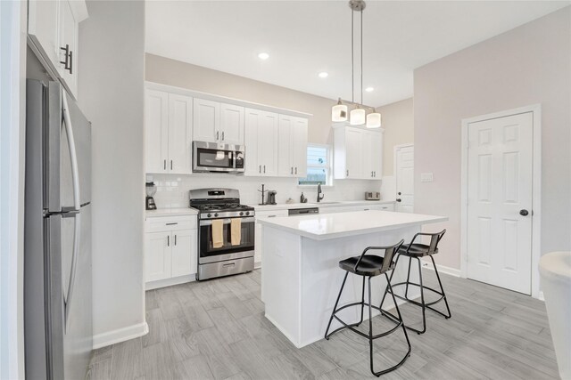 kitchen with stainless steel appliances, a breakfast bar, a sink, white cabinets, and light countertops