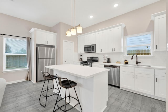 kitchen with a kitchen island, a sink, appliances with stainless steel finishes, tasteful backsplash, and a kitchen bar