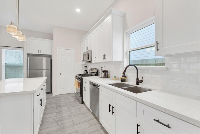 kitchen with white cabinetry, decorative backsplash, stainless steel appliances, and a sink