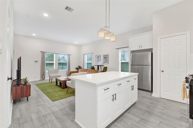 kitchen featuring visible vents, white cabinets, a kitchen island, stainless steel appliances, and light countertops