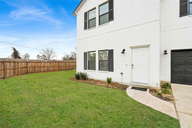 doorway to property featuring a yard, brick siding, and fence