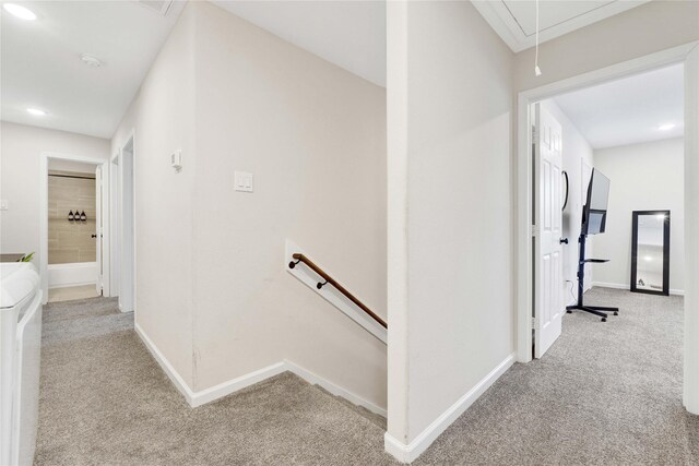 hallway featuring carpet, an upstairs landing, attic access, and baseboards