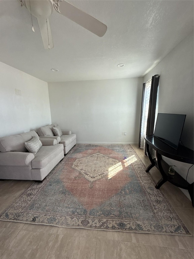 living room with ceiling fan and baseboards