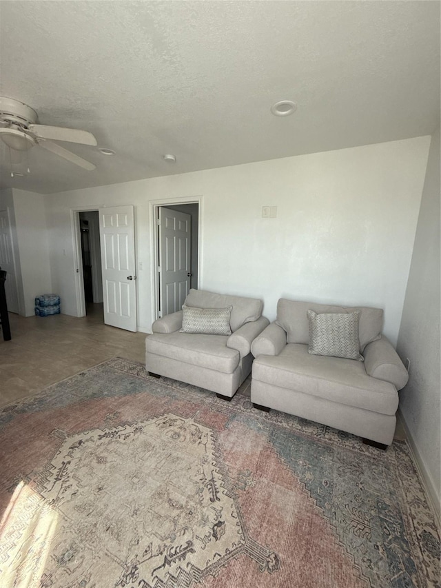 living area featuring ceiling fan and a textured ceiling