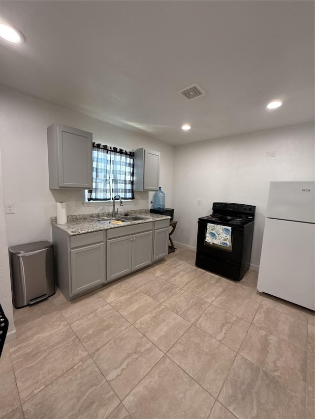 kitchen with freestanding refrigerator, gray cabinets, a sink, and black / electric stove