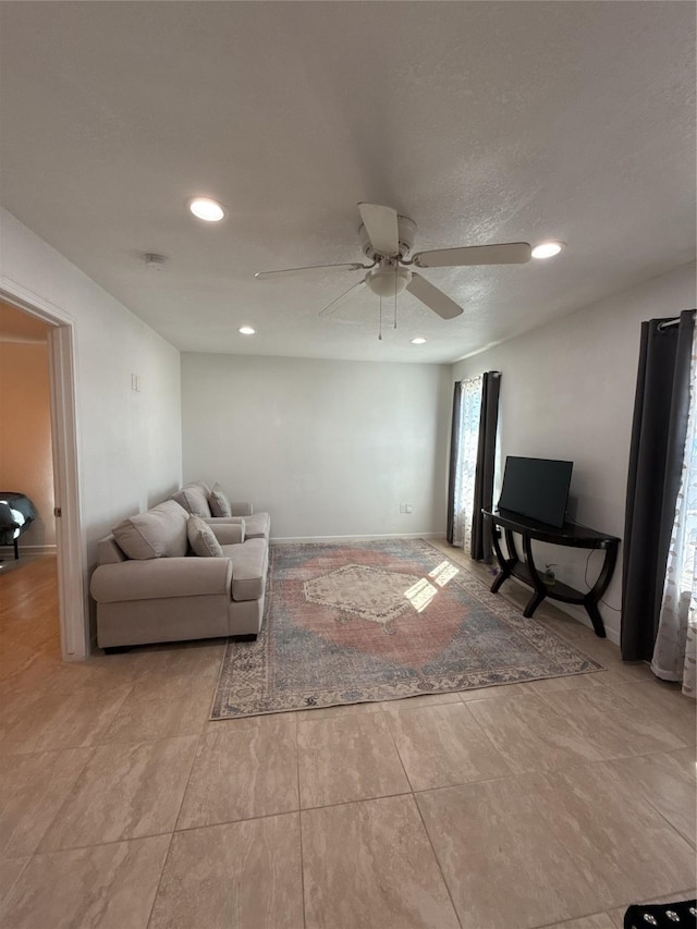 living area featuring ceiling fan, baseboards, and recessed lighting